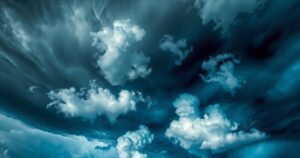 Dramatic thunderstorm clouds over a landscape, showcasing nature's power with blues and greys, embodying atmospheric dynamics.
