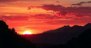 A vibrant sunset over a mountainous landscape with silhouette trees, depicting a journey of hope and exploration.