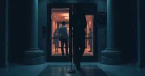 A tension-filled hotel scene with a closed door, shadowy figures outside, dim lighting, and muted colors to evoke unease.