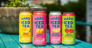 A refreshing assortment of hard iced tea cans in flavors like Lemon, Peach, and Raspberry, set against a summer backdrop.
