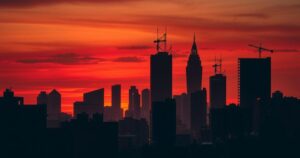 Silhouetted city skyline against an orange twilight sky, representing conflicts and resilience in a war-torn landscape.